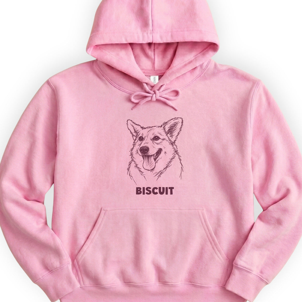 The Portrait Hoodie in Light Pink with a portrait of a corgi and the name Biscuit